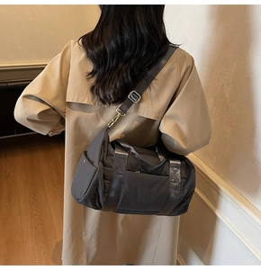 Detail of dark grey quilted nylon bag showing adjustable strap and golden buckles