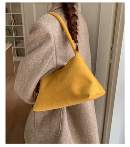 Detail of yellow matte faux suede shoulder bag with long strap worn on a tweed blazer