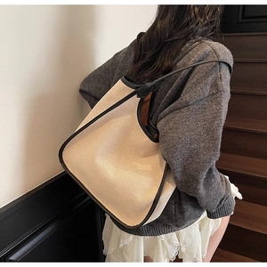 Détail du grand sac cabas beige avec bandoulières en cuir noir porté par le mannequin