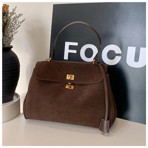 Détail d'un sac à main en daim marron foncé avec fermoir doré et poignée supérieure élégante
