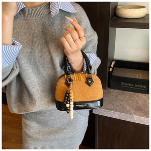 Detail of shell handbag with quilted pattern and decorative wooden bead tassel charm