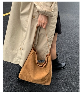 Gros plan d'un sac seau en daim marron avec plaque métallique dans un style street chic