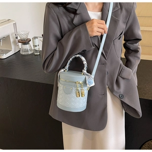 Detail of light blue bucket bag with woven texture and scarf wrapped handle shown with outfit