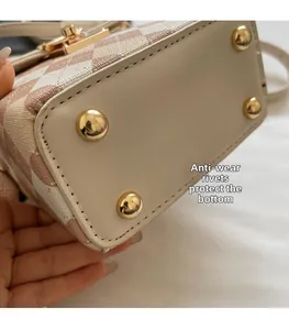 Detail view of mini bag bottom with protective gold metal rivets and pink check pattern