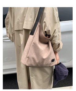 Détail d'un grand sac seau en daim sable avec une large bandoulière noire
