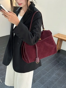 Détail de la texture en daim bordeaux et de la boucle dorée du sac à main rétro chic