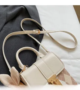 Detail of a cream quilted mini bag with adjustable shoulder strap and gold clasp buckle