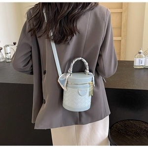 Detail of light blue cylinder bucket bag featuring woven PU texture and silk scarf handle