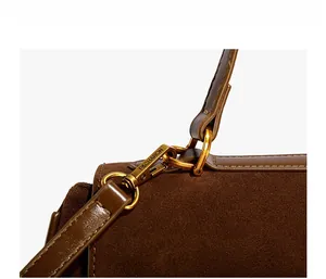 Détail du crochet en métal doré et de la bandoulière en daim sur sac marron