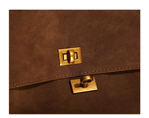 Gros plan du fermoir tournant doré vintage et surpiqûres sur sac en daim marron