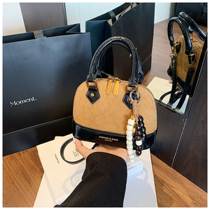 Close-up of quilted shell bag with wood bead charms and polished black patent handles