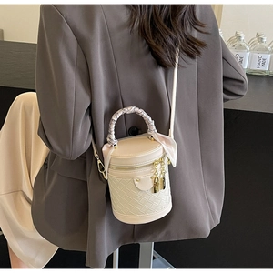 Detail of a beige cylinder bucket bag with quilted leather and silk scarf handle