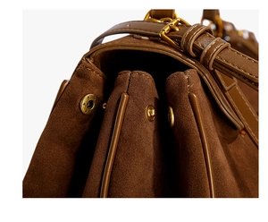Détail du sac à bandoulière en daim marron avec soufflets et fermoir doré élégant