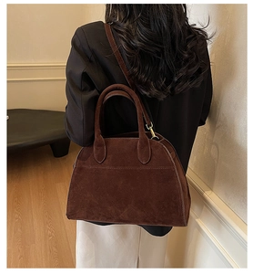 Detalle de bolso tote marrón mate con herrajes dorados y textura de costura fina