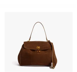 Détail d'un sac à main en daim marron foncé avec fermoir rotatif en métal et poignée lisse