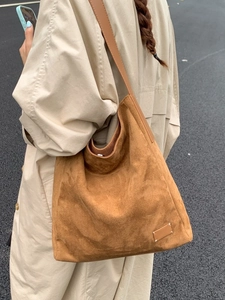 Grand sac cabas en daim marron avec surpiqûres à quatre coins porté par un modèle