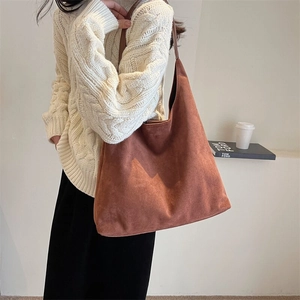 Minimalist brown suede oversized shoulder bag shown on model in a modern urban setting