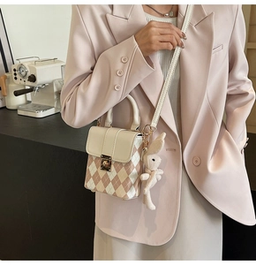 Detail of mini quilted crossbody bag with golden rotary lock and plush rabbit charm