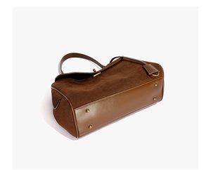 Vue détaillée du sac en daim marron foncé avec des pieds de protection en métal doré au bas
