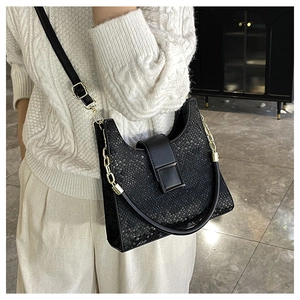 Détails du sac à bandoulière noir texture serpent avec chaîne dorée porté par un mannequin