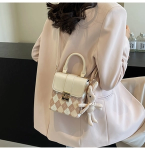 Detail view of mini quilted crossbody bag with knit rabbit charm on a pink blazer