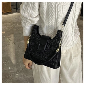 Détail du sac noir texture serpent avec grande boucle et bandoulière en chaîne