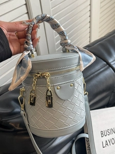 Light blue cylinder bucket bag with quilted weaving and scarf-wrapped handle detail