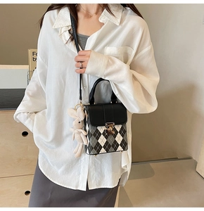 Detail of checkered crossbody bag with leather flap and white rabbit charm accessory