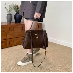 Détail d'un sac à main vintage marron mat avec boucle dorée dans un décor d'intérieur