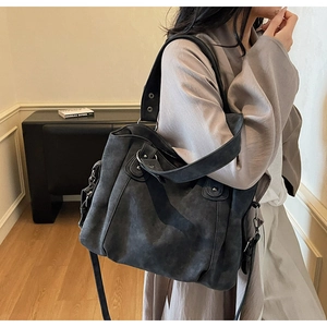 Détail d'un sac cabas en suédine gris foncé avec boucle métallique et bandoulière