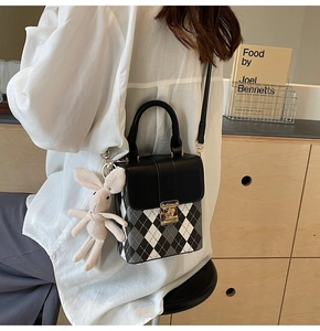 Detail of argyle crossbody bag with gold twist lock and cute knitted rabbit charm