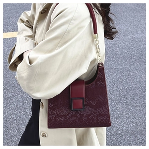 Détail du sac bordeaux en peau de serpent avec chaîne dorée et boucle carrée élégante