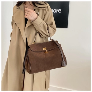 Gros plan du sac bandoulière marron mat avec boucle dorée et détail de texture en daim