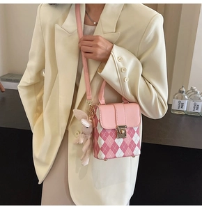 Detail of pink quilted mini bag with gold heart clasp and white plush rabbit charm