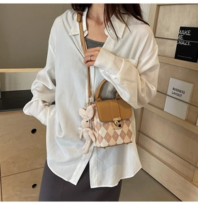 Detail of quilted mini crossbody bag with metal lock and plush rabbit charm