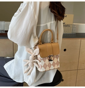Detail of quilted texture, metal flip lock and cute bunny pendant on the small crossbody bag