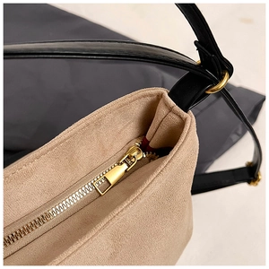 Macro shot of gold zipper detail and black leather strap on khaki suede tote bag