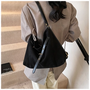 Close-up of a matte black canvas tote with adjustable leather strap and gold buckle
