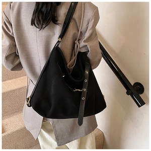 Macro view of matte black tote bag detail featuring gold buckle and leather strap