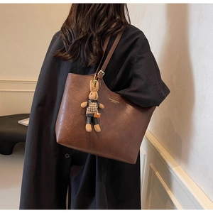 Detail of deep brown PU leather tote bag with FASHION & BAGS print and rabbit charm
