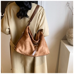 Macro view of brown frosted suede tote bag with leather strap and golden metal buckle detail