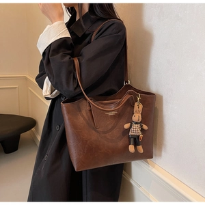 Brown leather tote bag featuring a cute rabbit charm and Fashion & Bags text on shoulder