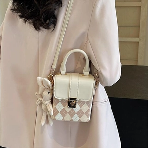 Quilted mini square bag with gold lock and cute bunny pendant shown from a side angle