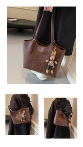 Detail of dark brown leather tote bag with metallic logo and cute rabbit charm