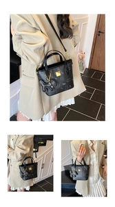Detail der schwarzen Tote-Tasche mit Bärendruck, Lychee-Textur und Goldanhänger