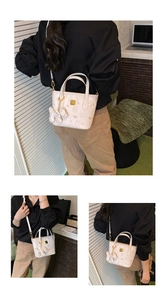 Detail einer cremeweißen Mini-Tote mit Bärenprint, Goldlogo und Plüschhund-Anhänger
