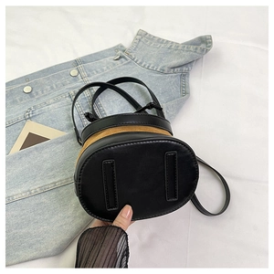 Détail du sac seau bicolore avec surpiqûres en cuir noir et daim marron élégant