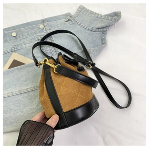 Détail du sac seau en daim marron avec surpiqûres jaunes et fermeture à cordon