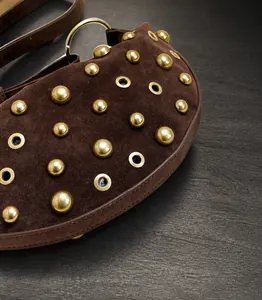 Detailed macro view of dark brown suede bag with gold studs and metal eyelets