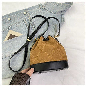Détail du sac seau en daim avec coutures contrastées et fermeture à cordon